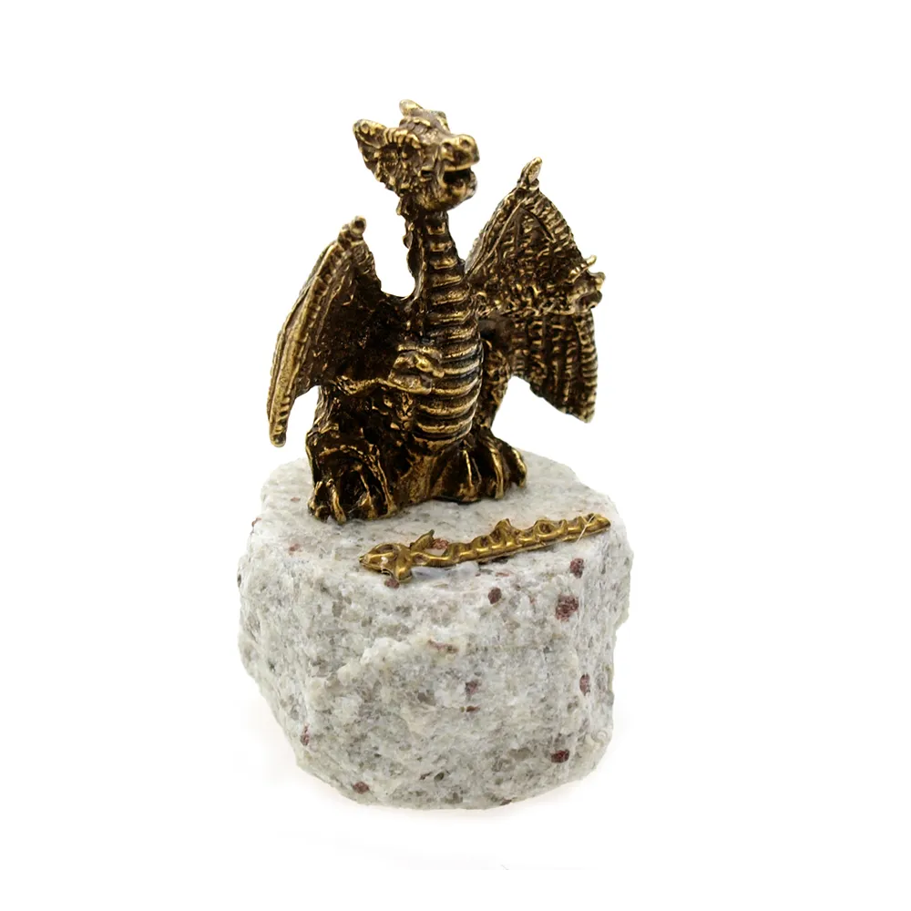 Metalowa figurka smoka wawelskiego z rozłożonymi skrzydłami na kamieniu granitowym